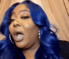 a woman with blue hair and hoop earrings is making a face .