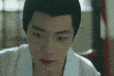 a close up of a man 's face wearing a white shirt and a black wig .