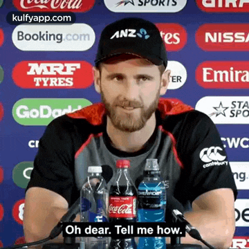 a man with a beard is sitting at a table with bottles of coca cola and water