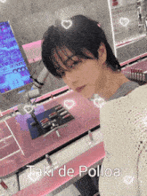 a man in a white sweater is standing in front of a pink table with the words taki de polloa on it