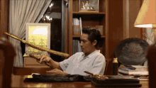 a man sitting at a desk holding a sword with a chinese symbol on it
