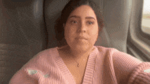 a woman wearing a pink sweater is sitting on a train