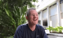a man wearing glasses is smiling in front of a building .