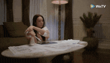 a woman sits at a table with papers and a wetv logo in the corner