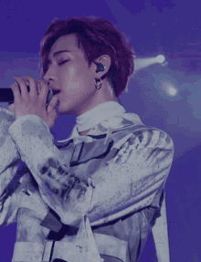 a man with red hair is singing into a microphone with a purple background