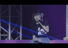 a girl singing into a microphone wearing a shirt that says ' dancing ' on the front
