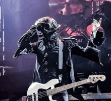 a man in a gas mask is holding a white bass guitar