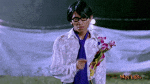 a man in a white shirt and purple tie holds a bouquet of flowers