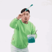 a man in a green sweater is holding a brush over his head .