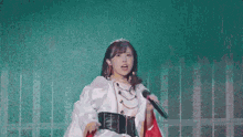 a woman in a crown is singing into a microphone on stage