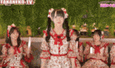 a group of girls are sitting on a couch in front of a sign that says takaneko-tv on it