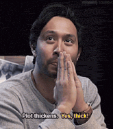 a man covering his mouth with his hands and says plot thickens yes thick