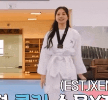 a woman in a taekwondo uniform is wearing a medal around her neck and smiling .