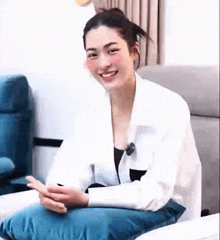 a woman is sitting on a couch with a pillow in her lap and smiling .