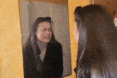 a woman is looking at herself in a mirror .