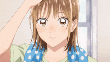 a girl with a blue polka dot towel around her neck looks at her hair