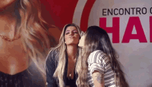 two women are kissing each other in front of a poster .