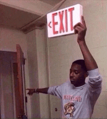 a man is holding an exit sign over his head in a room .