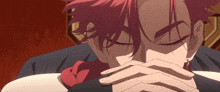 a man with red hair has his eyes closed and his hands covering his face