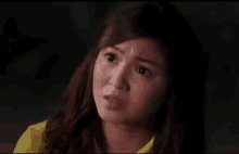 a woman in a yellow shirt is making a funny face .