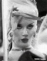 a black and white photo of a woman getting her hair cut by a hairdresser