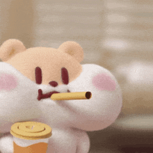a stuffed animal with a straw in its mouth is holding a cup .