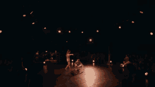 a man and a woman are standing on each other 's shoulders on a stage
