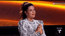 a woman in a white dress is sitting in front of a microphone with her hands folded .