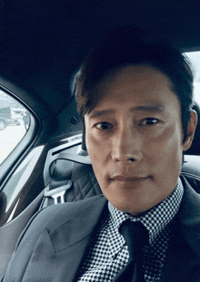 a man in a suit and tie is sitting in the back of a car