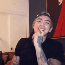 a man with a tattoo on his arm is smiling with his finger on his mouth