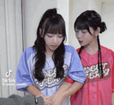 two young girls are standing next to each other holding hands .