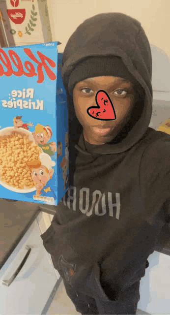 a young boy wearing a black hoodie is standing next to a box of kellogg 's cereal