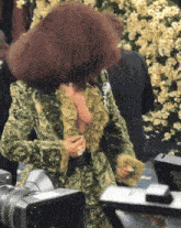 a woman in a green and gold dress is being filmed by a camera