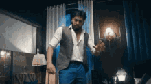 a man with a beard is dancing in a room