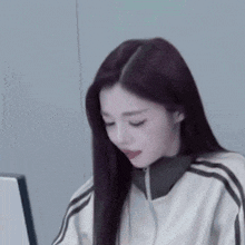 a woman with long dark hair is sitting in front of a computer screen .
