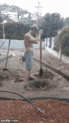 a shirtless man is digging a hole with a shovel ..