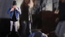 a man wearing a denim jacket and a black beanie with the letter n on it