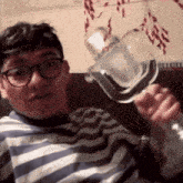 a man in a striped shirt is holding a bottle of vodka in his hand