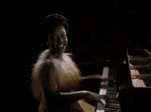 a woman in a yellow dress is playing a grand piano