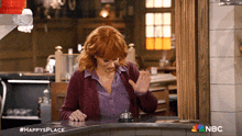 a woman stands behind a counter with a nbc logo on the bottom