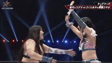 two female wrestlers are giving each other a high five in front of a sign that says stardom