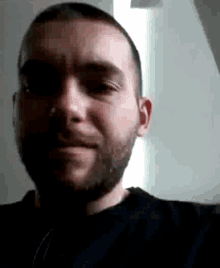 a man with a beard wearing a black shirt is smiling