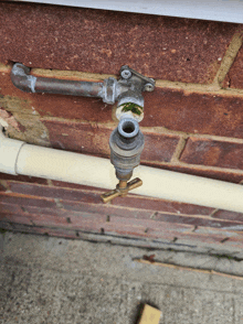 a faucet is attached to a brick wall with a white pipe