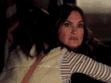 a woman in a striped shirt is hugging another woman and making a funny face