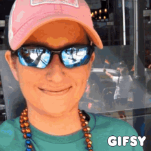 a woman wearing sunglasses and a pink hat has a gifsy sticker below her