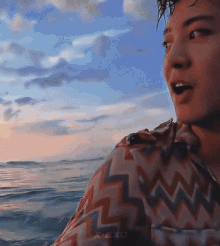 a man in a shirt with a chevron pattern is looking out over the ocean