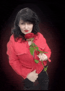 a woman wearing a red jacket is holding a red rose