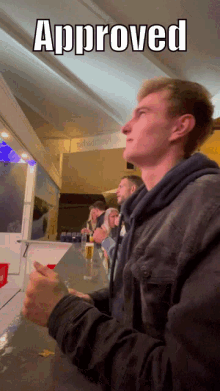 a man sitting at a counter with the word approved above him