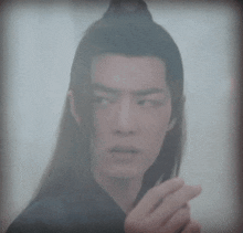 a man with long hair is looking through a window and making a surprised face .