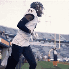 a football player wearing a white jersey and a helmet is running on a field .